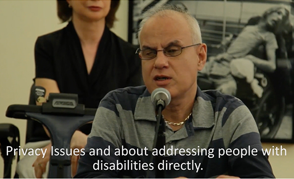A seated man speaking into a microphone
